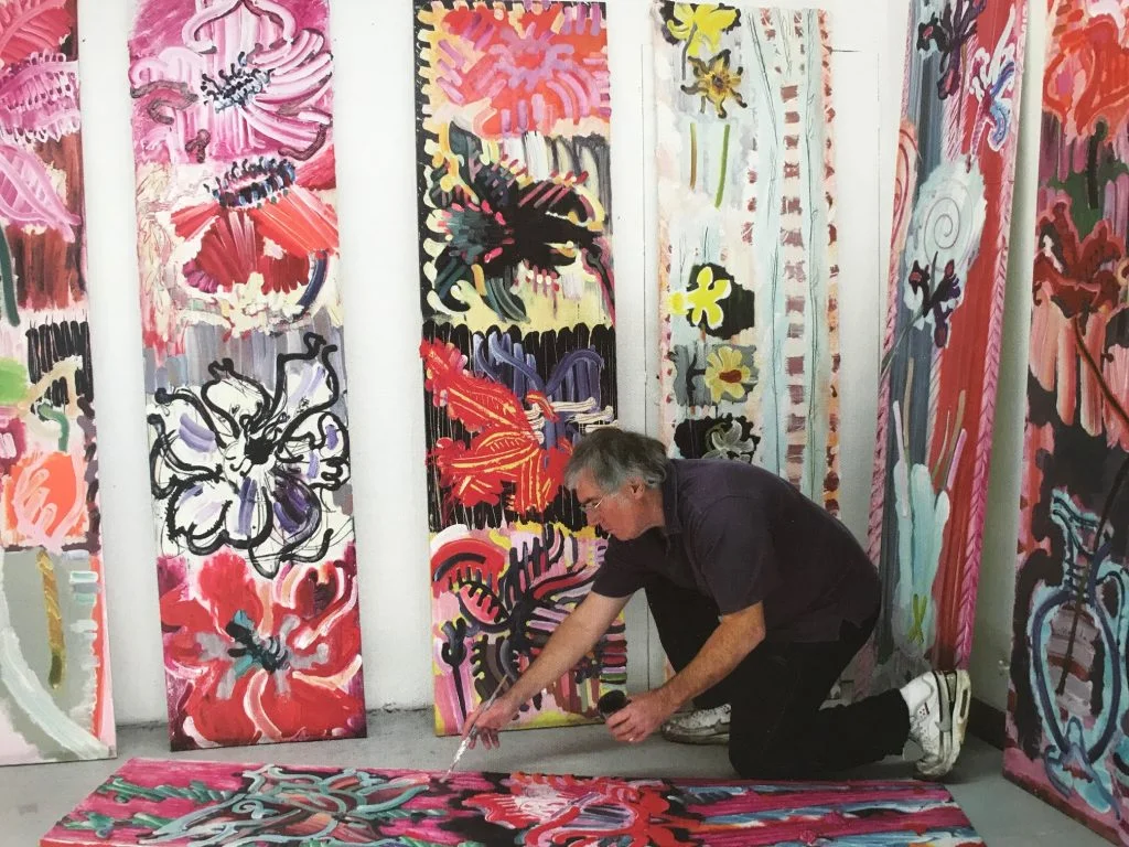 Contemporary artist, Edward Kelly, works on colourful floral artwork on the floor of his studio